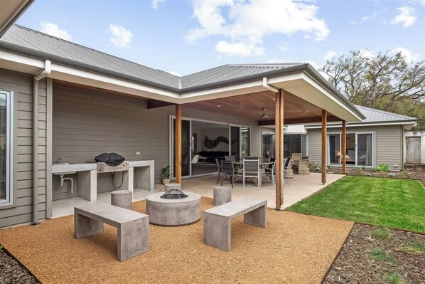 A modern house with a covered patio, outdoor seating, and a fire pit.