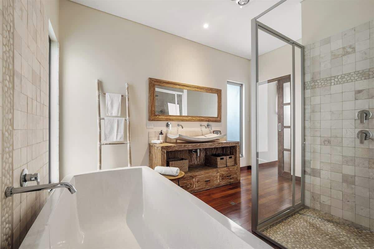 Une salle de bain moderne avec une grande baignoire, un meuble-lavabo en bois, une cabine de douche en verre et un miroir au-dessus du meuble-lavabo.