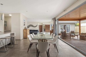 A modern kitchen with a glass dining table, white chairs, and a kitchen island.