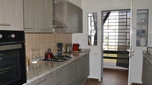 A modern kitchen with granite countertops, stainless steel appliances, and a view through a sliding door to a balcony.