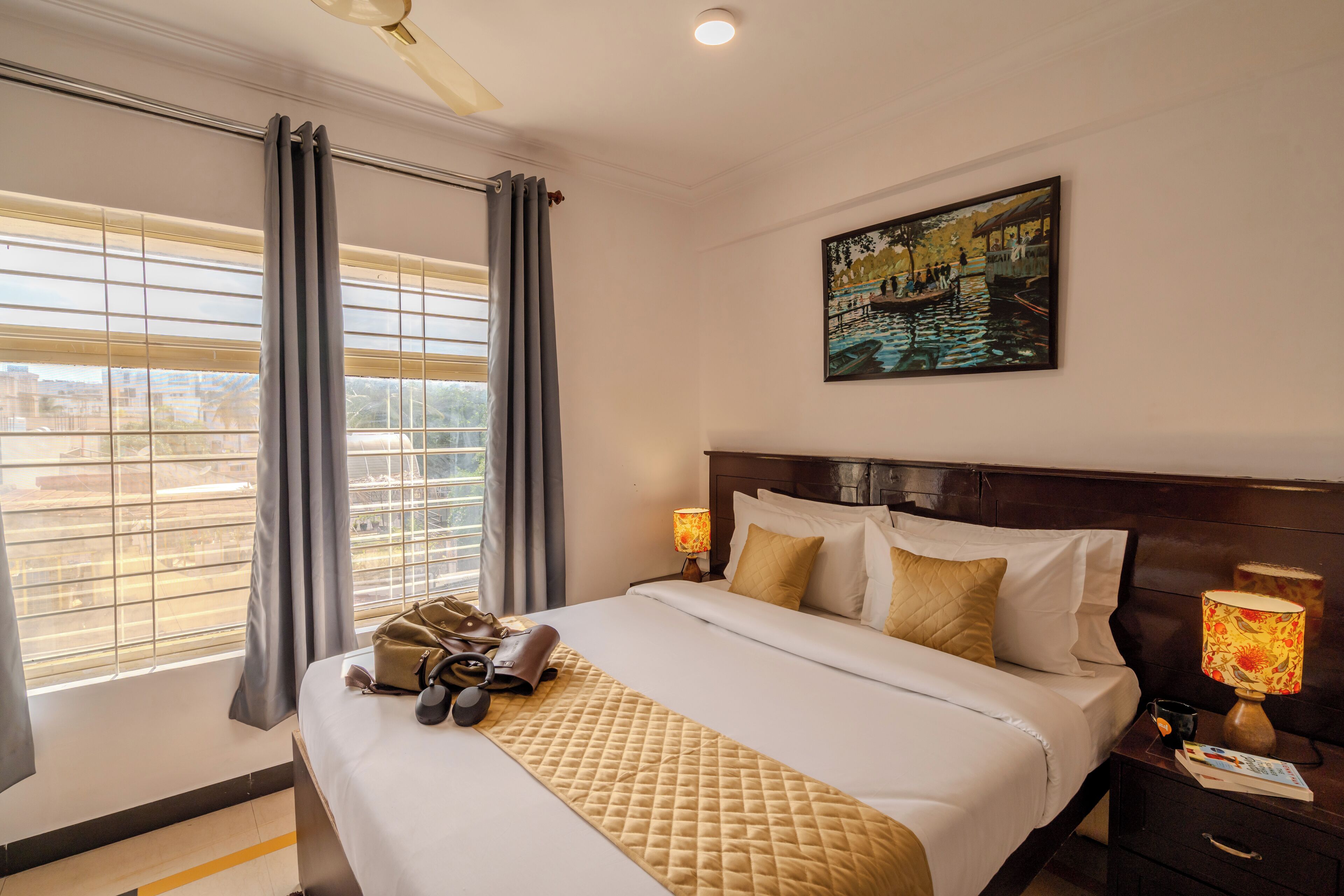 A hotel room with a large bed, a painting on the wall, and a window with curtains.