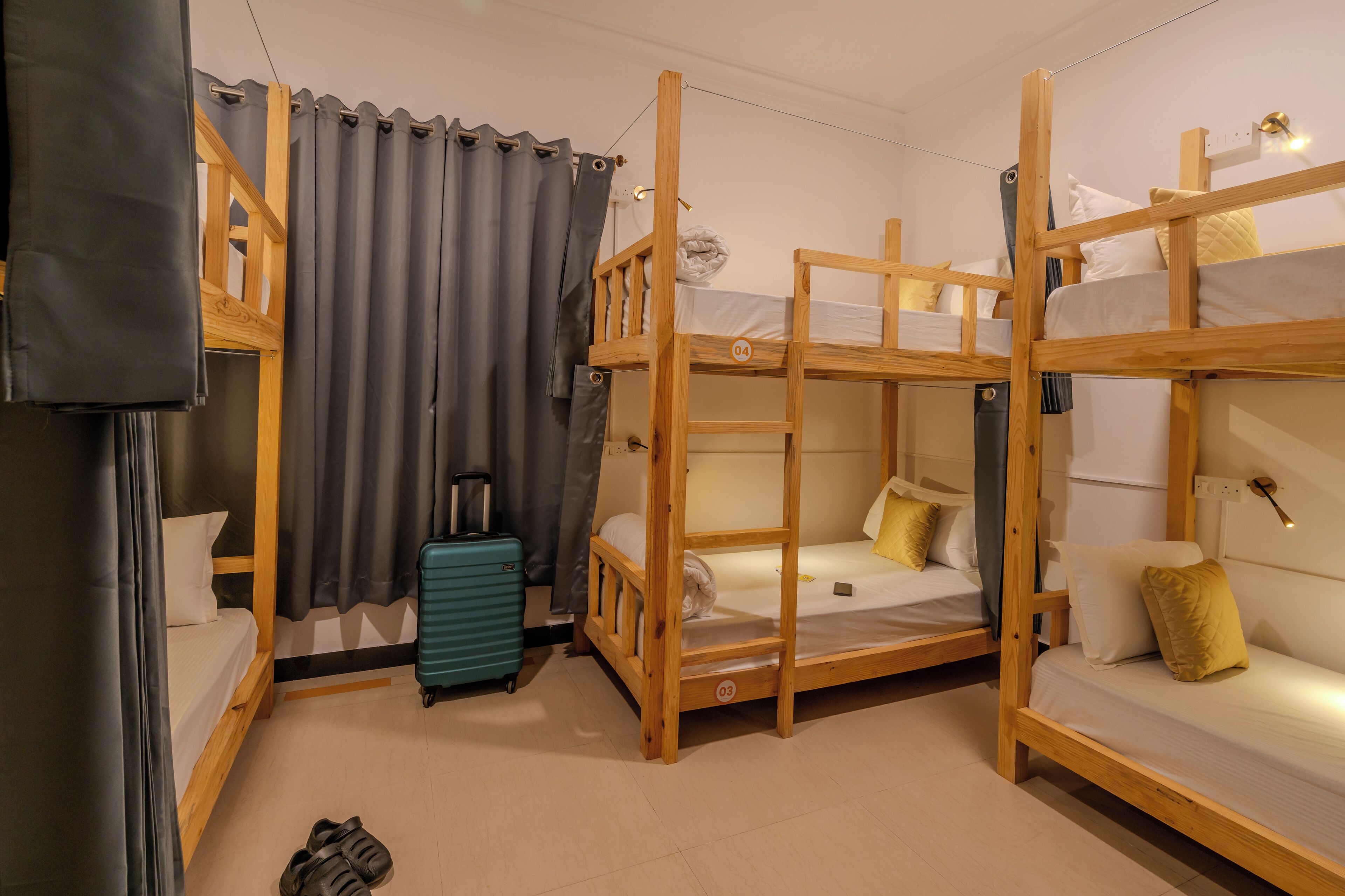 Une chambre avec des lits superposés, une valise et un rideau.