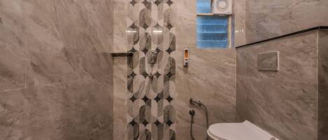A bathroom with a marble wall, a shower, and a toilet.