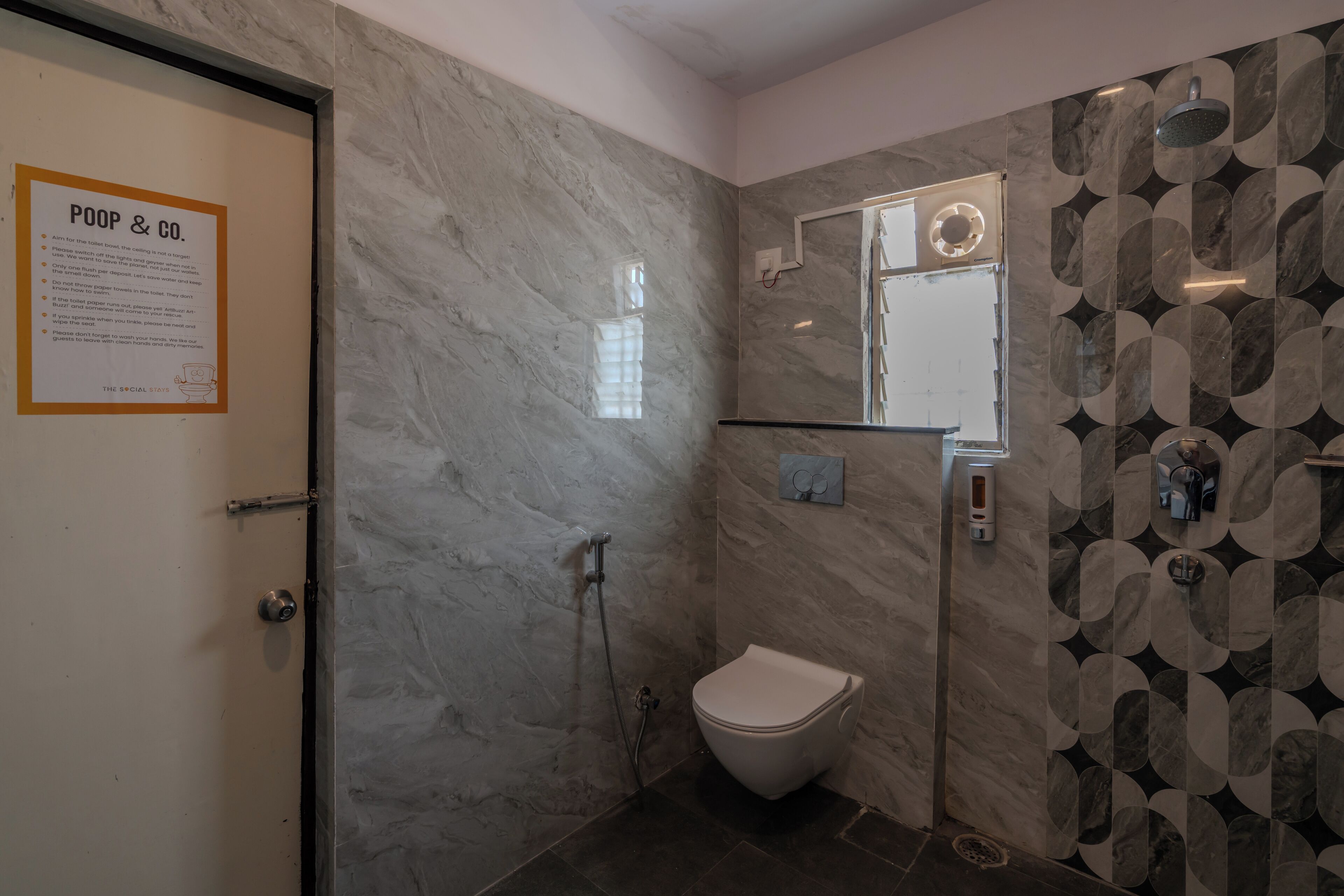 Un baño con inodoro, ducha y espejo. Hay un cartel en la puerta.