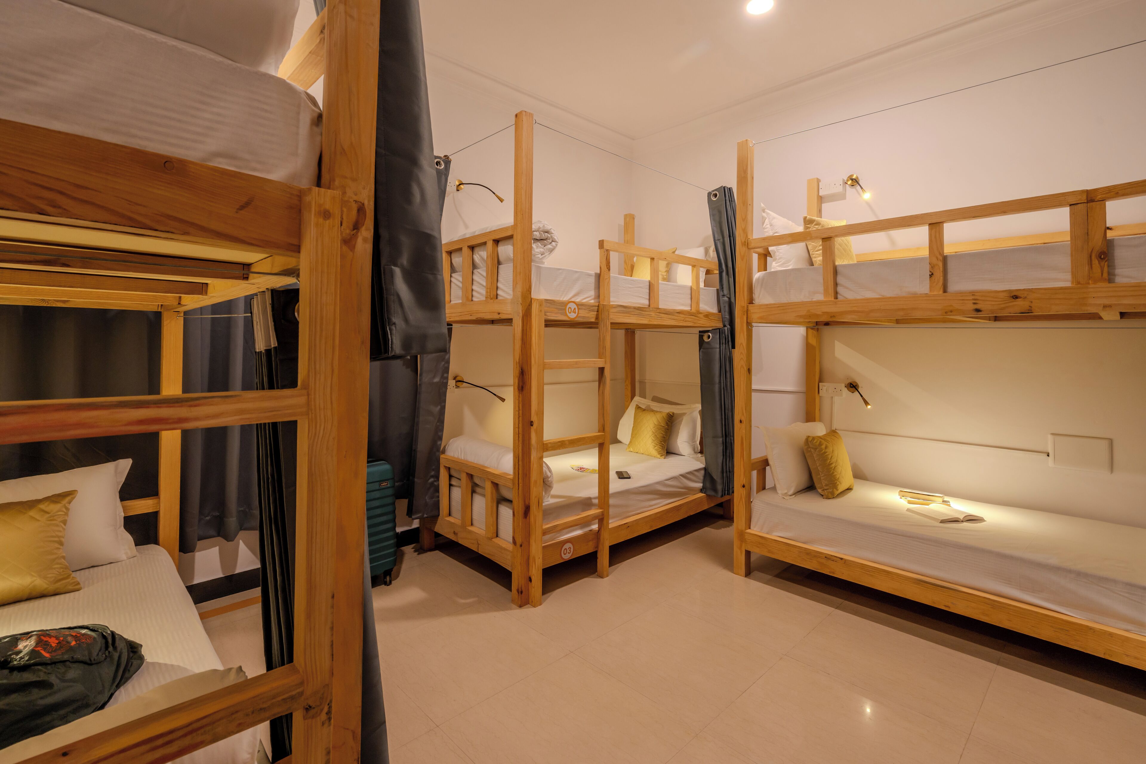 A room with three bunk beds, a small desk, and a curtain.