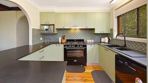 A modern kitchen with green cabinets, a black stove, and a large island.