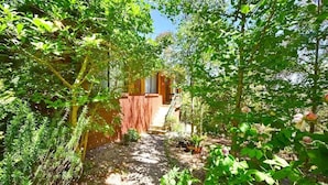 A garden pathway leading to a building with a brick wall and a wooden door.