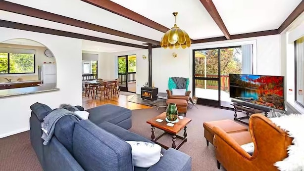 A spacious living room with a fireplace, comfortable seating, and large windows offering a view of the outdoors.