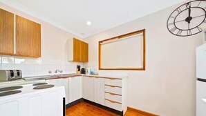 Uma cozinha moderna com armários brancos, piso de madeira e um relógio de parede.