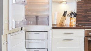Una cocina con un refrigerador abierto, un microondas y una encimera de madera con utensilios de cocina.