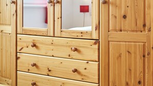 Un armario de madera con varios cajones y un espejo.
