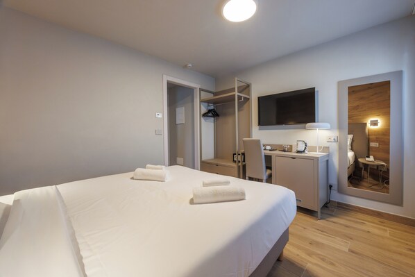 A hotel room with a large bed, a desk, a chair, a TV, and a mirror. - Lift Hotel  (Sauze d'Oulx)
