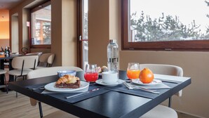 A breakfast table with croissants, a white bowl, a glass of red juice, a glass of orange juice, and a bottle of water. - Lift Hotel  (Sauze d'Oulx)