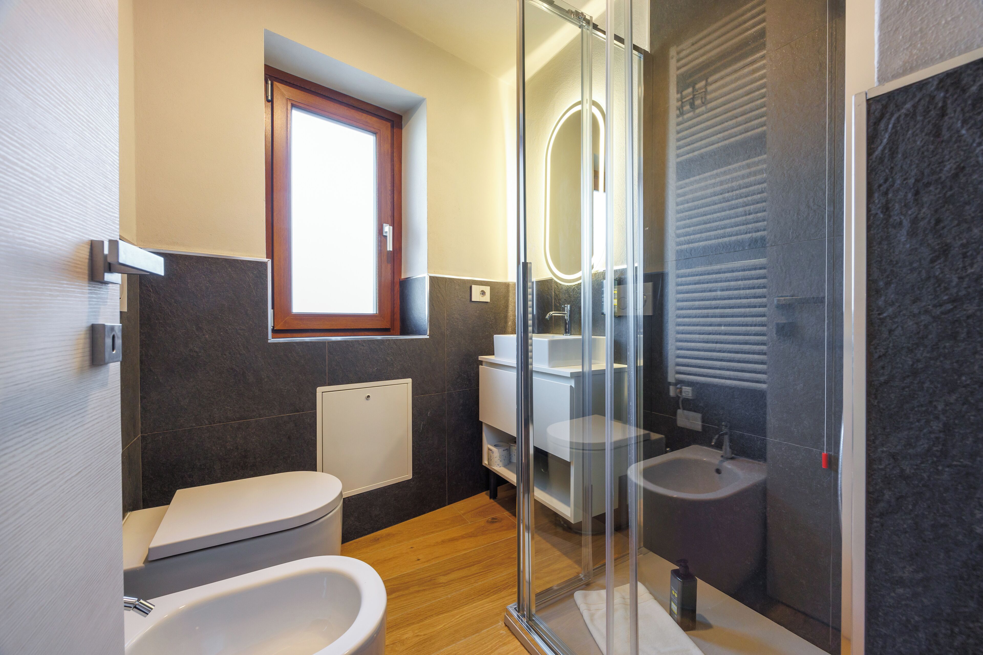 A modern bathroom with a toilet, bidet, and glass-enclosed shower.