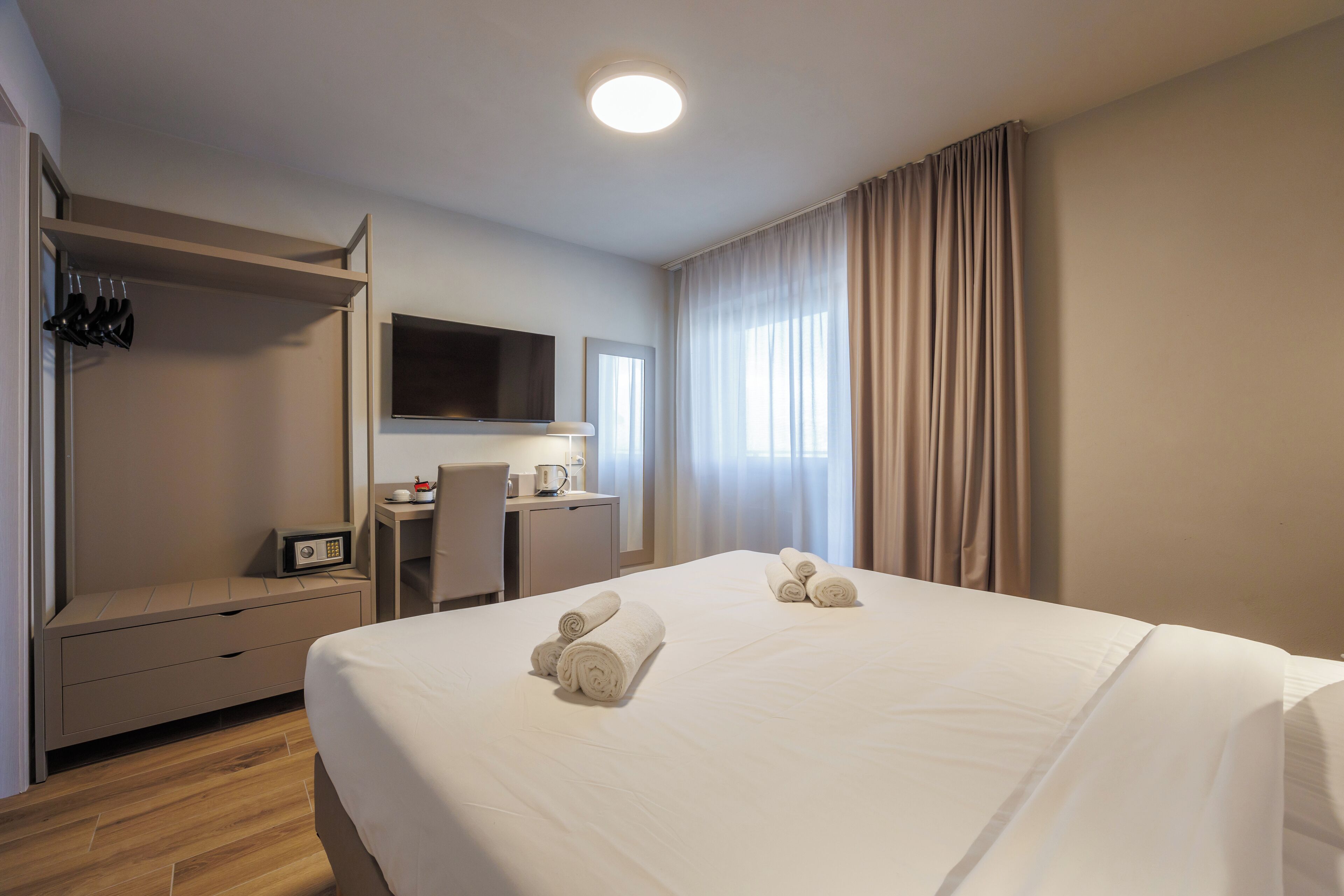 Une chambre d’hôtel équipée d’un lit, d’un bureau, d’une chaise, d’une télévision et d’une armoire.