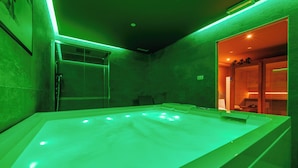 A spa area with a large, illuminated hot tub and a glass-enclosed shower area. - Lift Hotel  (Sauze d'Oulx)