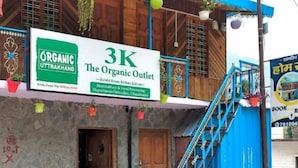 A building with a sign for 'The Organic Outlet' and a staircase leading to a blue-roofed upper level. - SANDEEP HOME STAY (Chakrata)