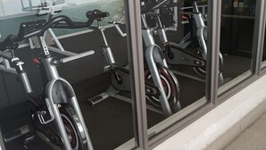 A row of stationary bikes inside a building with large windows. - Hoe Sweet Home (Cape Town)