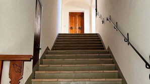 Un escalier doté d’une rampe en bois et d’une autre en métal, menant à une porte en bois située en haut.