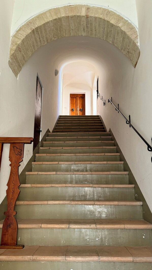 A staircase with a wooden handrail and a metal handrail, leading to a wooden door at the top. - In the center of Assisi apartment with wonderful terrace (Assisi)