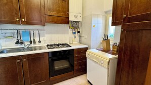 Une cuisine avec des meubles de rangement en bois, une cuisinière à gaz, un lave-vaisselle et un évier.