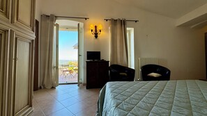 A hotel room with a bed, a desk with a TV, a chair, and a view of the outdoors. - In the center of Assisi apartment with wonderful terrace (Assisi)