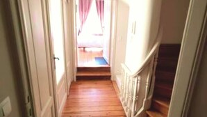 A narrow hallway with wooden flooring leading to a staircase. - Double room Delay garden view (Bruxelles)