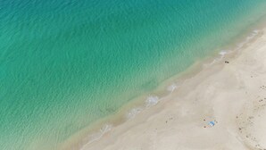 An aerial view of a beach with clear turquoise water and a sandy shore. - Solace Jervis Bay - 3BR relaxed beach side living (Vincentia)