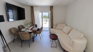 En moderne stue med spiseområde, sofa og fjernsyn monteret på væggen.