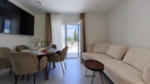 En moderne stue med et spiseområde, en sofa og et fjernsyn ophængt på væggen.