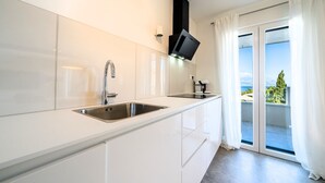 A modern kitchen with a stainless steel sink, white cabinets, and a black range hood.