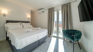 A hotel room with a bed, a chair, a TV, and a window with curtains.