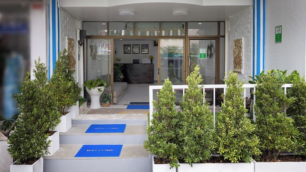 L’entrée d’un hôtel, avec un comptoir d’accueil, des portes vitrées et des marches menant au hall d’entrée.
