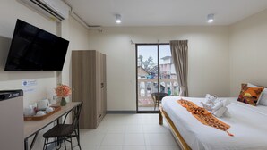 Une chambre d’hôtel avec un lit, un bureau avec une télévision, une armoire et une vue sur l’extérieur.