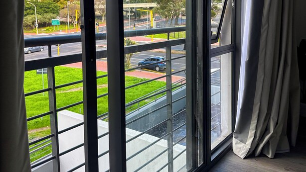 A room with a large window overlooking a road and greenery, with a view of distant mountains.