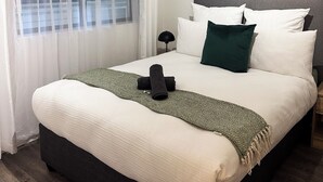 A neatly made bed with a patterned throw, a dark headboard, and a green pillow.