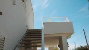 Ein weißes Gebäude mit einer Treppe, die zu einem Balkon führt.