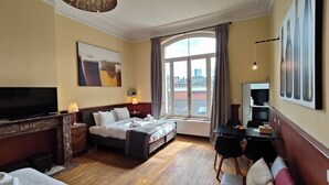 Une chambre d’hôtel avec un lit, une télévision, un bureau et une grande fenêtre.