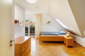 A bedroom with a bed, bedside table, dresser, and a window with a view of the outside.
