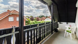 A balcony with a view of houses, a white table with chairs, and a black railing.