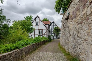 A cobblestone path leading to traditional half-timbered houses with a stone wall on one side.