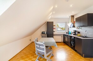 A modern kitchen with a dining area, a washing machine, and a view of the outside.