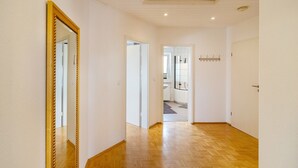 A hallway with wooden flooring, a large mirror, and doors leading to other rooms.