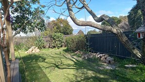 Ein Garten mit einer Holzterrasse, einem Holzstapel und einem Zaun.