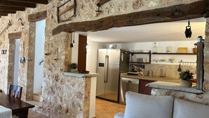 Un intérieur rustique en pierre, comprenant un coin cuisine, une table à manger et un canapé.