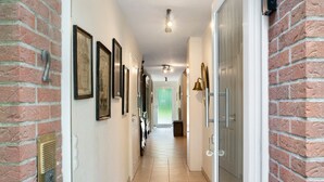 A hallway with brick walls, framed pictures, a doorbell, and a door. - Country House 'Friesenhof' with Shared Terrace, Private Garden, and Wi-Fi (Wangerland)