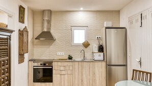 A compact kitchen with a built-in oven, a stainless steel refrigerator, a microwave, and a window above the sink.