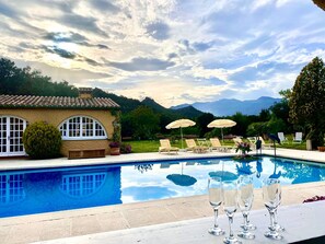 A pool with lounge chairs and umbrellas, a building with arched windows, and a mountainous backdrop. - Bosque Apartment with Mountain Views, Wi-Fi, and Air Conditioning (Girona)
