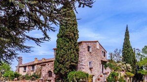 A stone building with a courtyard, surrounded by trees and potted plants.