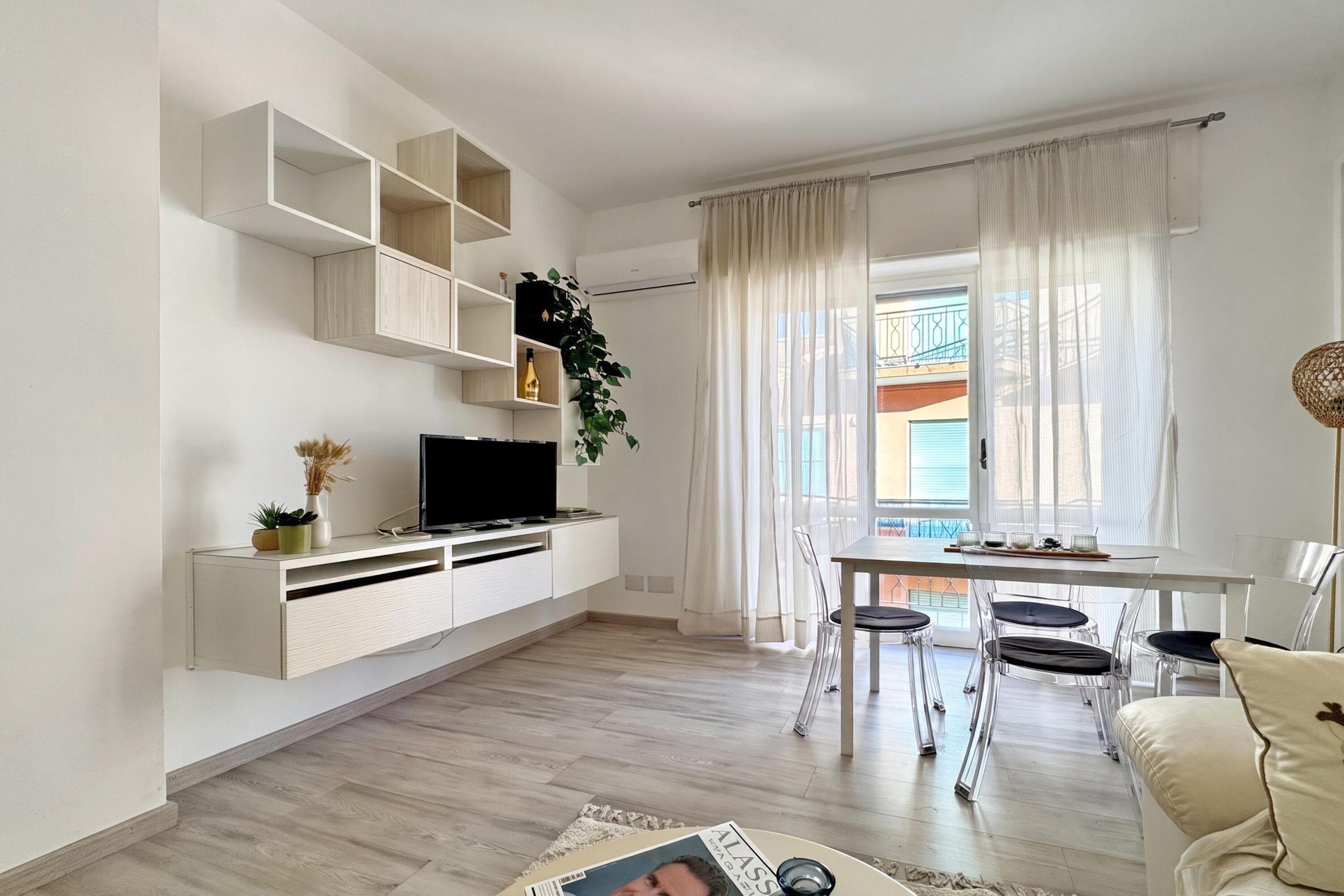 Un soggiorno moderno con TV a schermo piatto, un tavolo da pranzo con sedie e un divano.